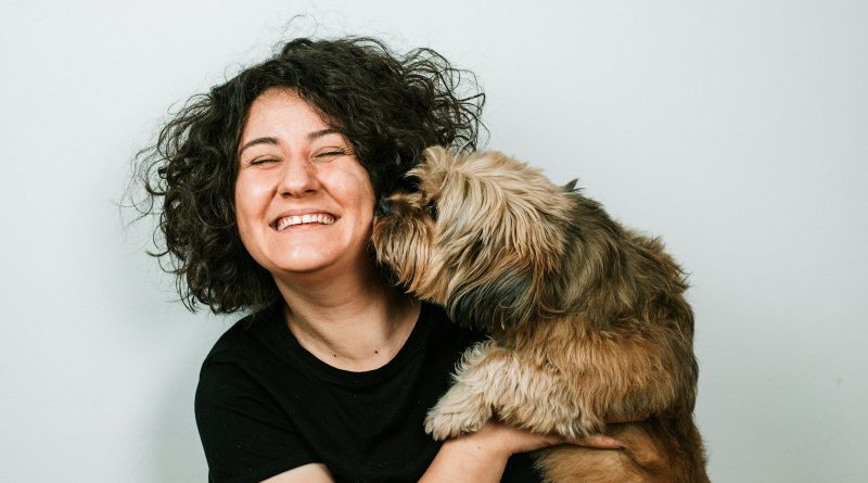dog kissing woman in black crew-neck shirt
